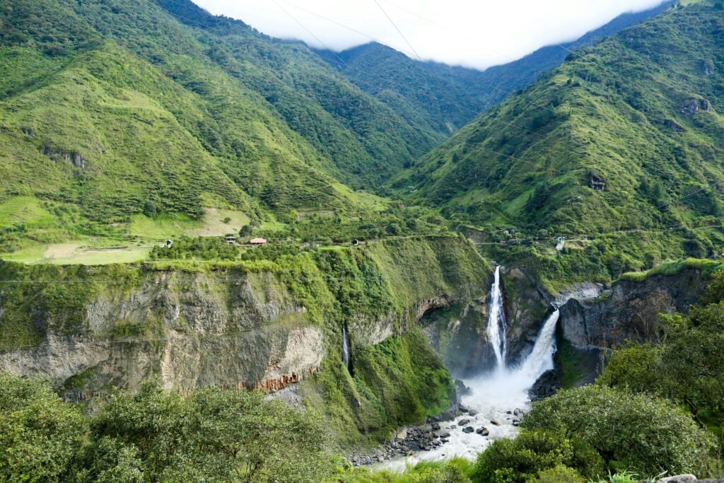 Stunning waterfall cascading in a lush Ecuadorian valley, surrounded by green mountains.